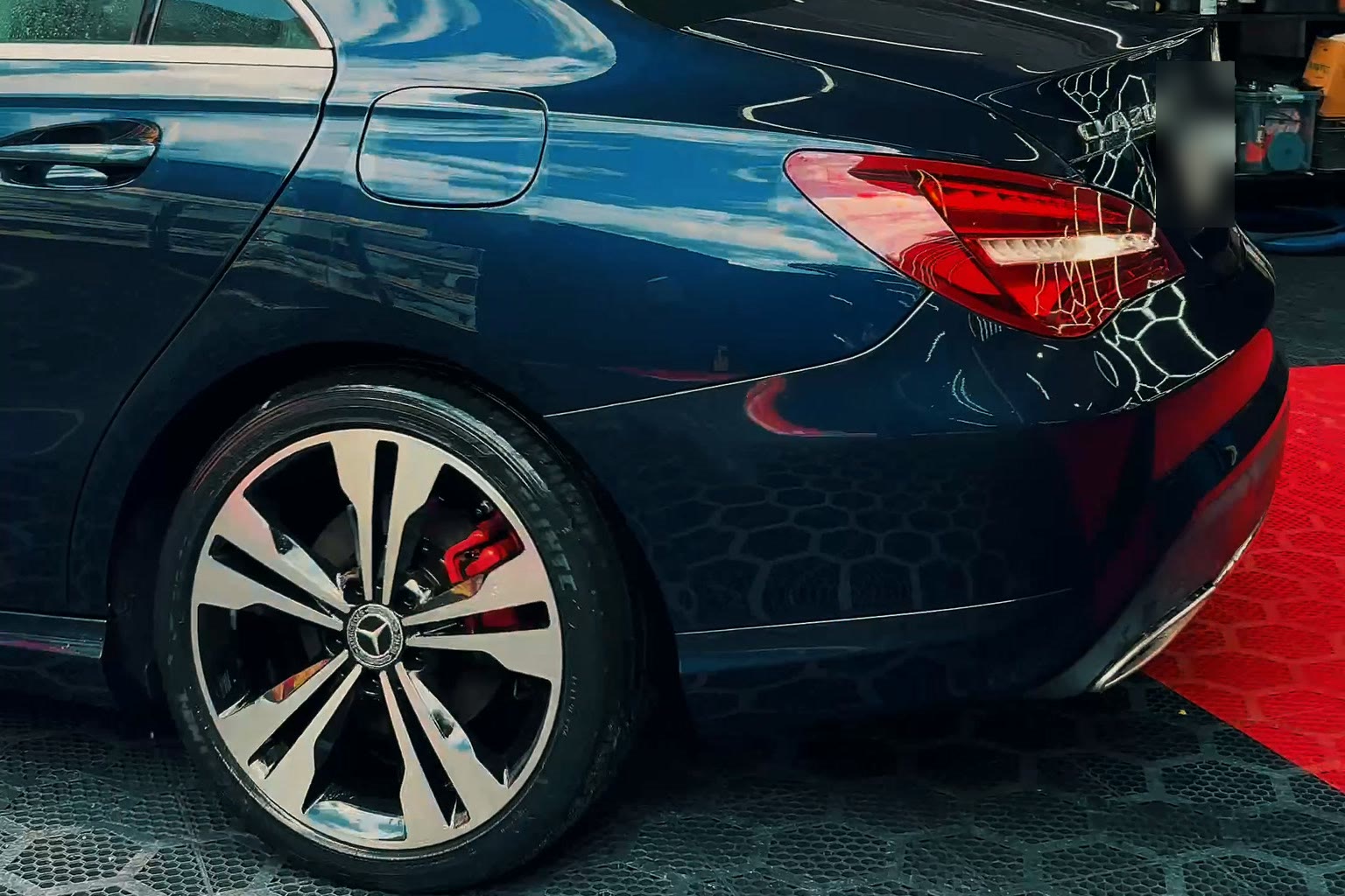 Lateral de um carro azul polido no estúdio da Pink, com reflexos nítidos
